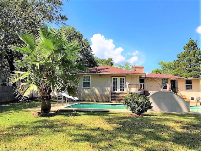 back of property featuring french doors, a yard, a chimney, fence, and an outdoor pool