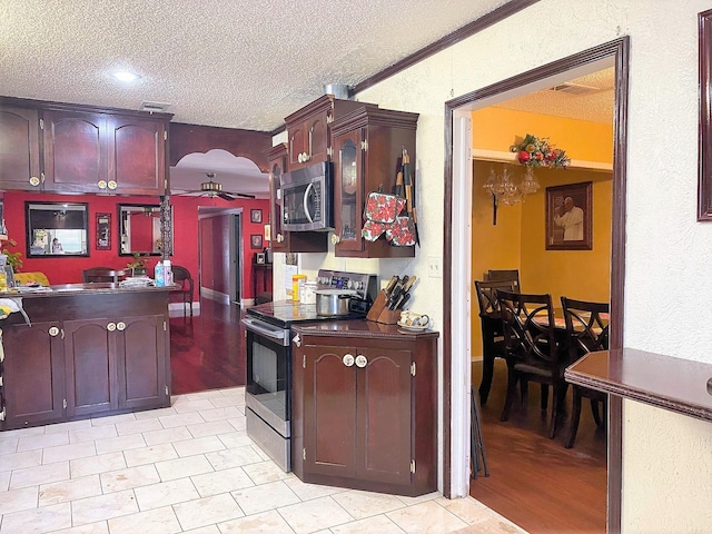 kitchen with arched walkways, stainless steel appliances, visible vents, ceiling fan, and a textured ceiling