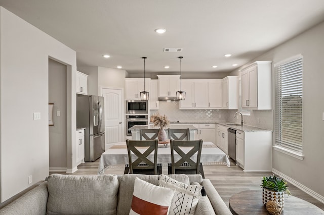 kitchen featuring a sink, visible vents, white cabinets, appliances with stainless steel finishes, and decorative backsplash