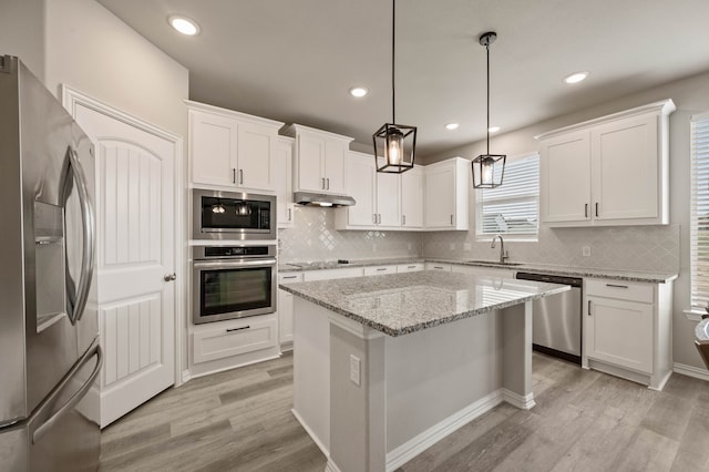 kitchen featuring light wood finished floors, appliances with stainless steel finishes, white cabinets, and a sink