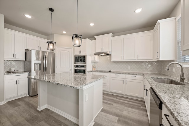 kitchen featuring appliances with stainless steel finishes, white cabinetry, a sink, and under cabinet range hood