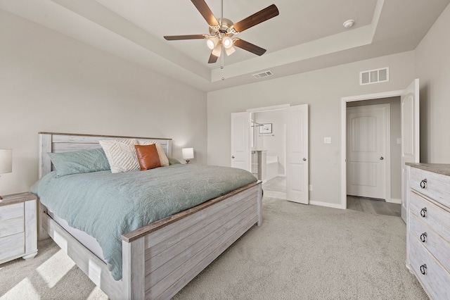 bedroom featuring light colored carpet, a raised ceiling, and visible vents