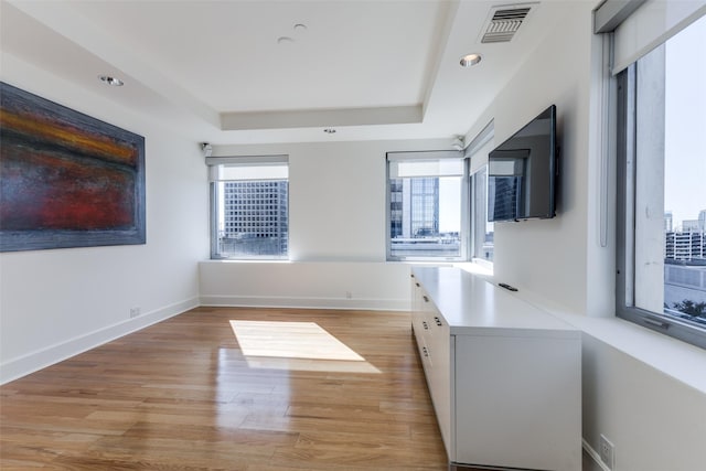 interior space featuring light wood finished floors, visible vents, baseboards, a tray ceiling, and recessed lighting