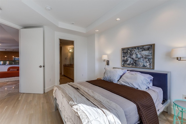 bedroom featuring baseboards, ensuite bath, and light wood-style floors