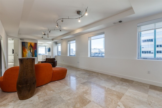 living room featuring rail lighting, a raised ceiling, visible vents, and baseboards