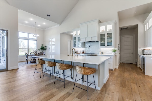 kitchen with a kitchen bar, light wood finished floors, and high vaulted ceiling