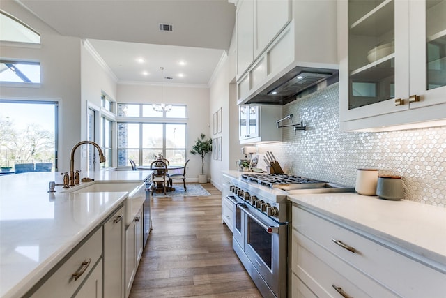 kitchen with double oven range, visible vents, custom exhaust hood, ornamental molding, and backsplash