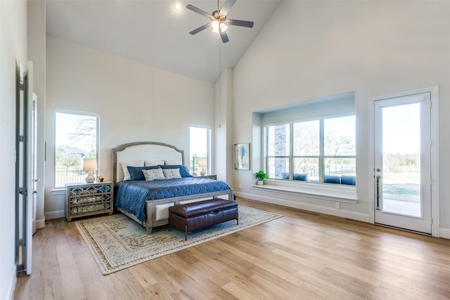 bedroom featuring wood finished floors, multiple windows, high vaulted ceiling, and access to exterior