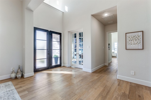 entryway with light wood finished floors, french doors, and baseboards