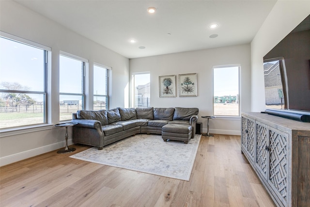 living area featuring light wood-style flooring, plenty of natural light, and baseboards