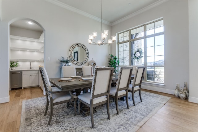 dining room with crown molding, baseboards, light wood-style flooring, arched walkways, and a notable chandelier