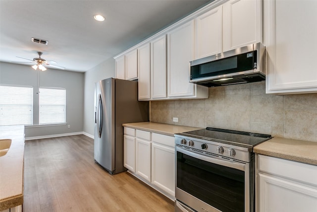 kitchen featuring appliances with stainless steel finishes, white cabinets, visible vents, and backsplash