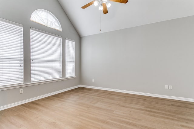 unfurnished room with a ceiling fan, vaulted ceiling, light wood-style flooring, and baseboards