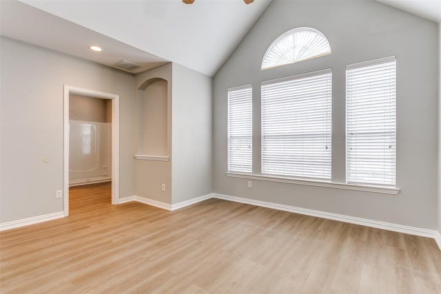 empty room with lofted ceiling, visible vents, a ceiling fan, light wood-type flooring, and baseboards