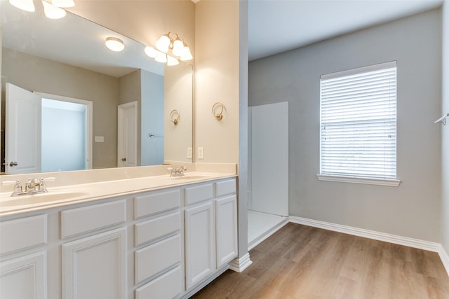 bathroom featuring double vanity, baseboards, a sink, and wood finished floors