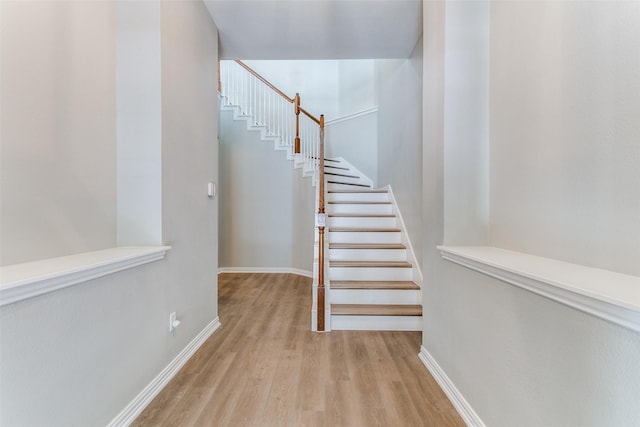 staircase with baseboards and wood finished floors