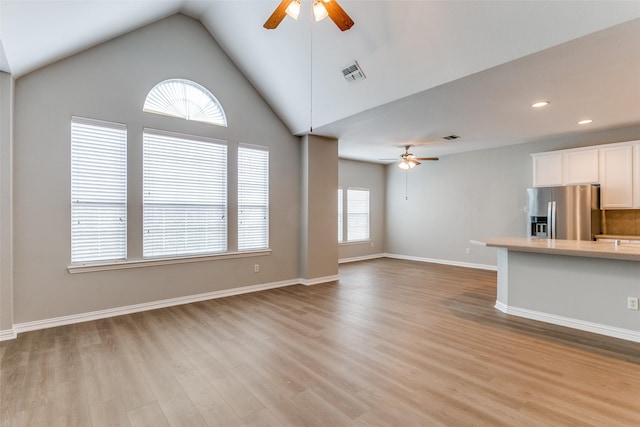 unfurnished living room with a ceiling fan, visible vents, light wood-style floors, and baseboards