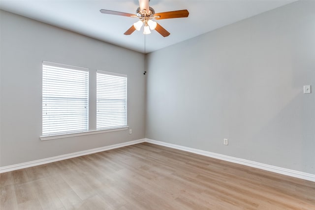 spare room with light wood-type flooring, a ceiling fan, and baseboards