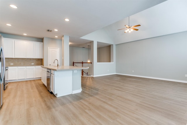 kitchen with open floor plan, light countertops, light wood finished floors, and backsplash