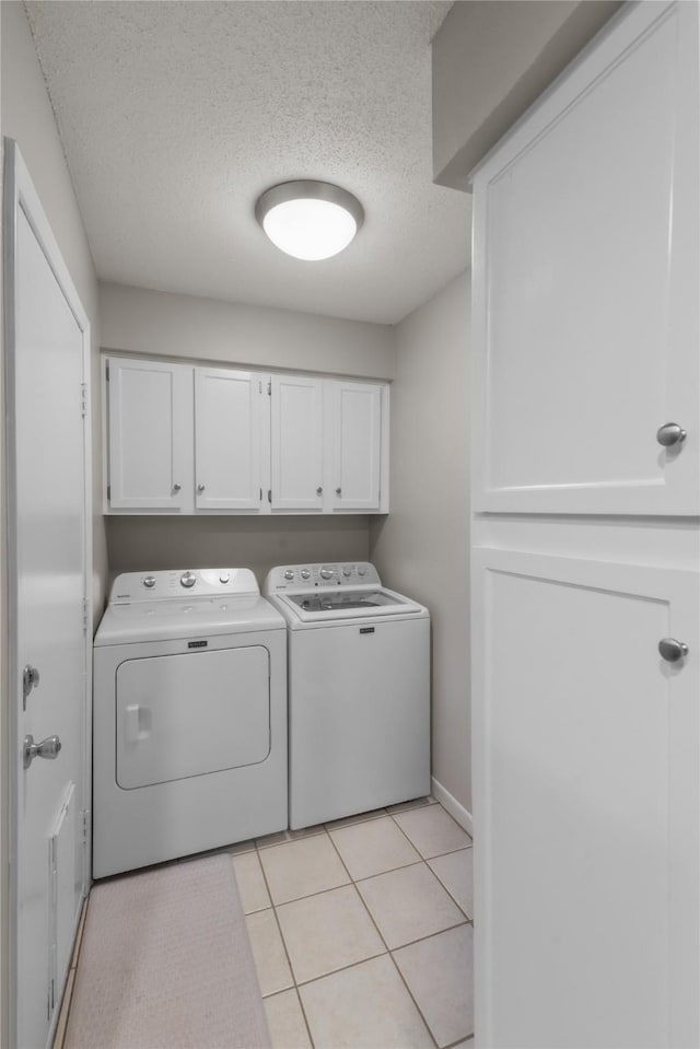 laundry area featuring cabinet space, light tile patterned floors, washer and clothes dryer, and a textured ceiling