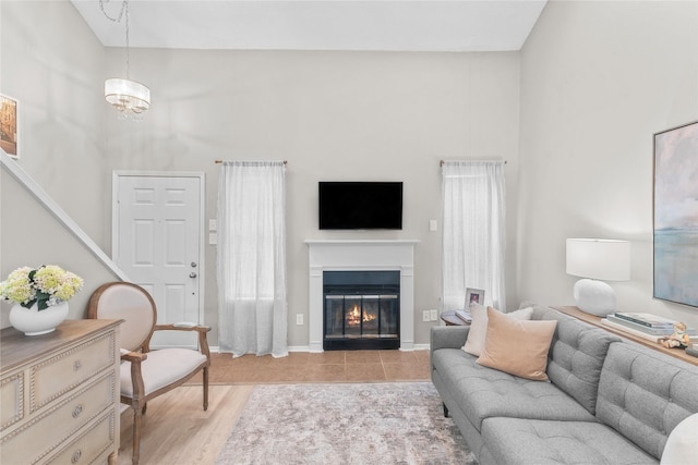 living room featuring light wood-style floors, stairs, a high ceiling, and a glass covered fireplace