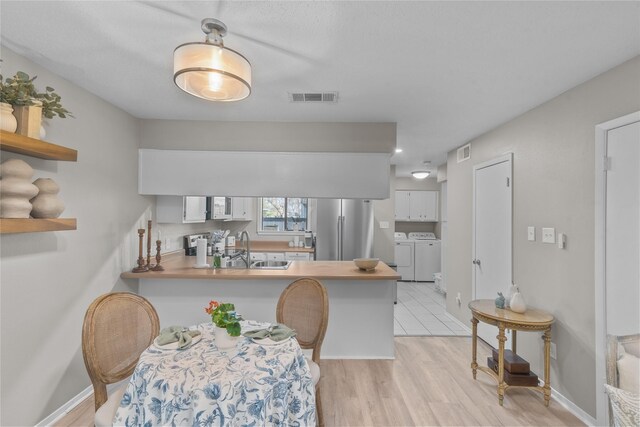 dining space featuring light wood-type flooring, visible vents, washer and clothes dryer, and baseboards