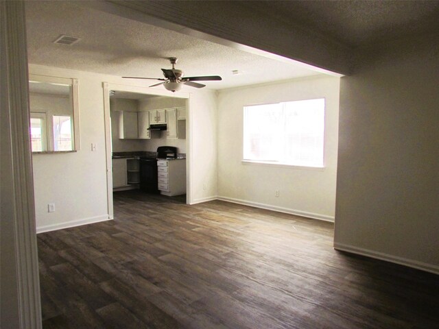 unfurnished living room with plenty of natural light, visible vents, dark wood finished floors, and a ceiling fan