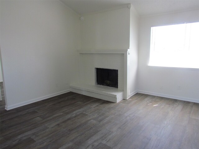 unfurnished living room featuring dark wood-type flooring, a fireplace, baseboards, and ornamental molding