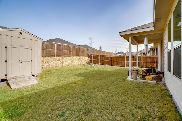 view of yard featuring a fenced backyard, an outdoor structure, and a storage shed