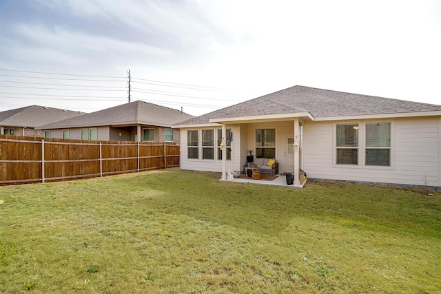 rear view of house with a patio area, roof with shingles, a lawn, and a fenced backyard