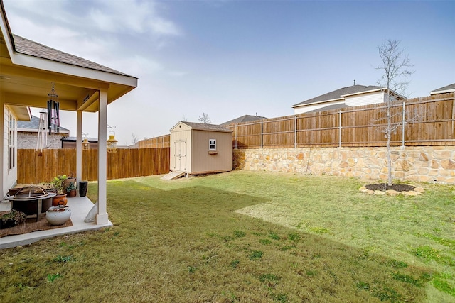 view of yard featuring a storage unit, a fire pit, an outdoor structure, a fenced backyard, and a patio area