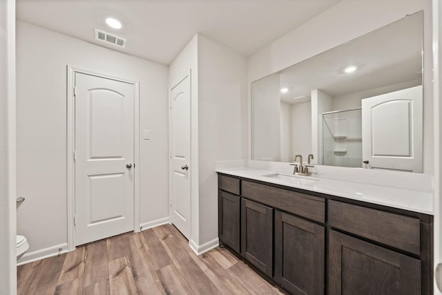 bathroom with visible vents, toilet, vanity, wood finished floors, and baseboards