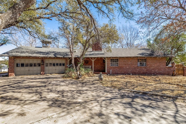 single story home with a garage, brick siding, a chimney, and driveway