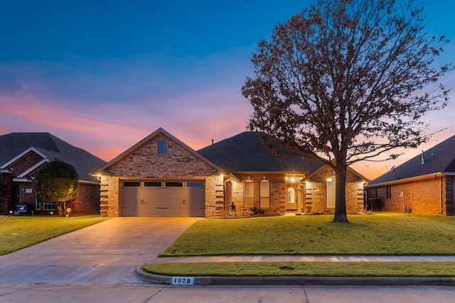 view of front of house with a garage, a front yard, concrete driveway, and brick siding