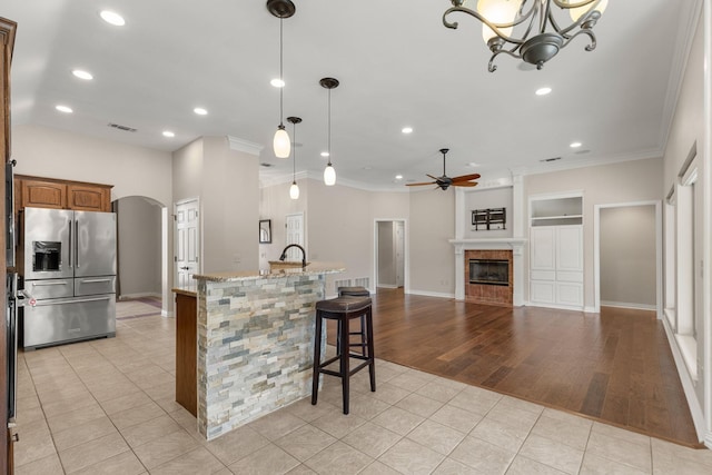 kitchen with stainless steel fridge, arched walkways, visible vents, a fireplace, and light tile patterned flooring