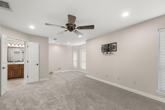 interior space featuring ensuite bathroom, recessed lighting, light carpet, visible vents, and baseboards