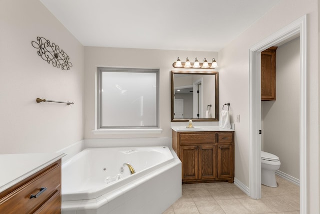 bathroom featuring toilet, vanity, tile patterned flooring, baseboards, and a tub with jets