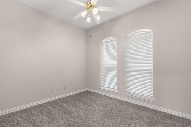 empty room with carpet flooring, a ceiling fan, and baseboards