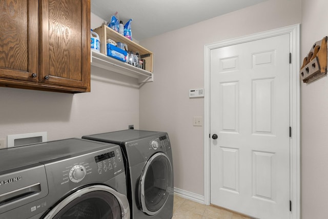 laundry area featuring light tile patterned floors, washing machine and clothes dryer, cabinet space, and baseboards