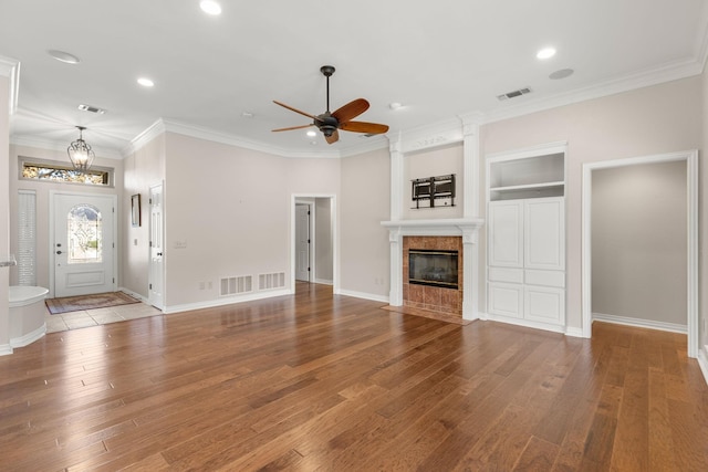 unfurnished living room with wood-type flooring, visible vents, and a tiled fireplace