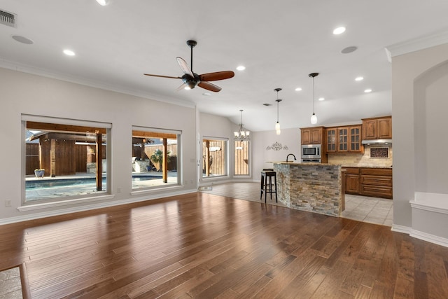 living area featuring baseboards, ceiling fan with notable chandelier, crown molding, light wood-style floors, and recessed lighting