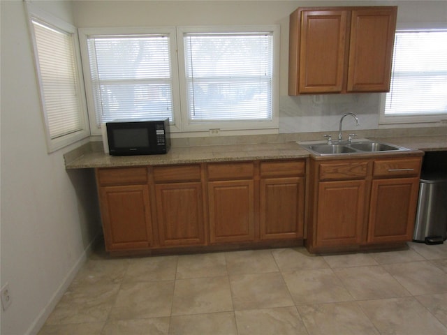 kitchen featuring black microwave, brown cabinets, a sink, and light countertops