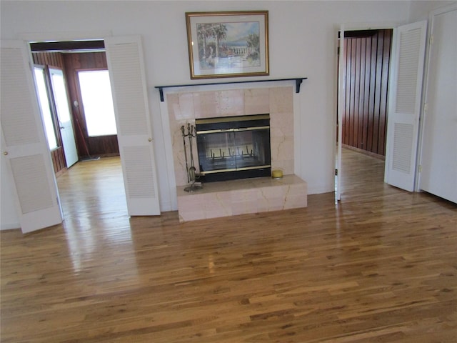 unfurnished living room with a tiled fireplace and wood finished floors