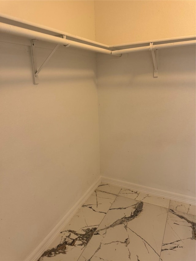 walk in closet featuring marble finish floor