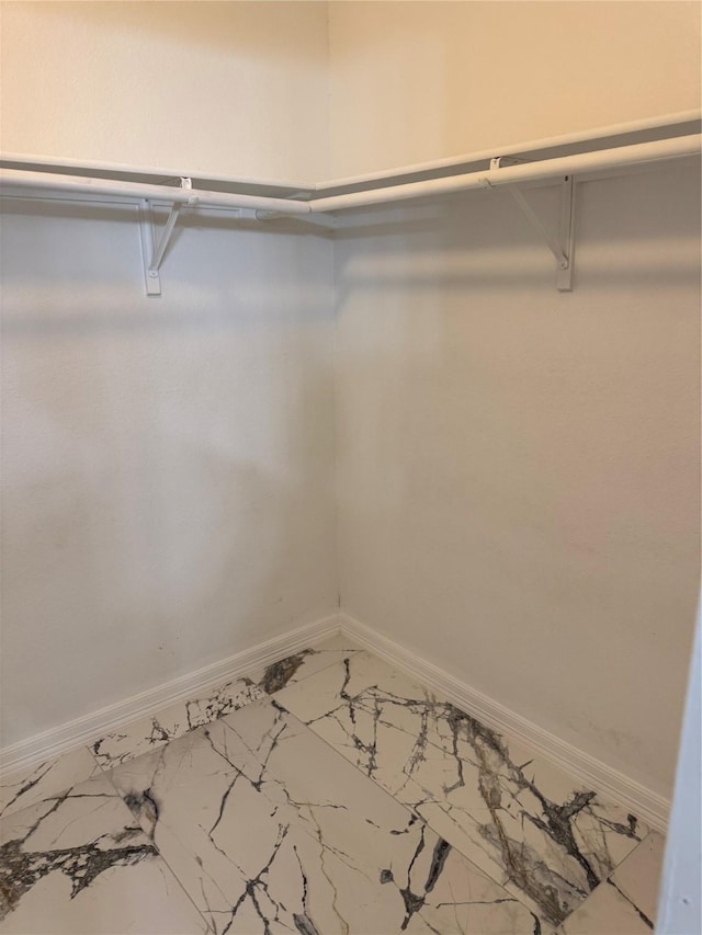 walk in closet featuring marble finish floor