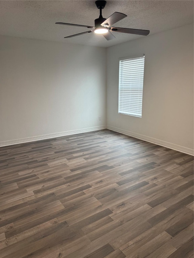 spare room with dark wood-style floors, a ceiling fan, baseboards, and a textured ceiling