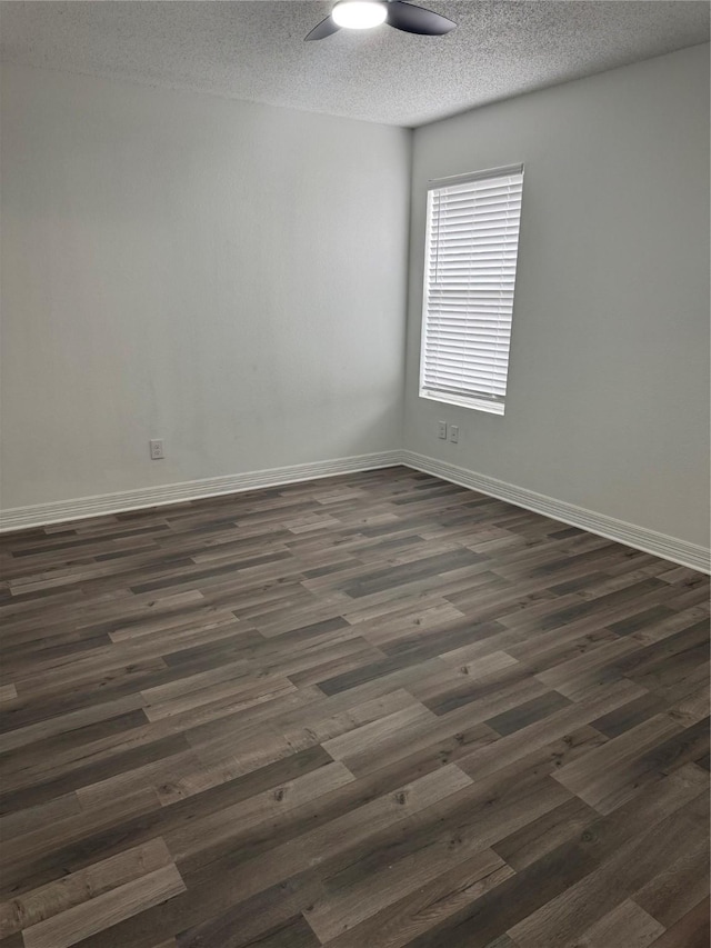 empty room featuring a ceiling fan, a textured ceiling, baseboards, and dark wood-type flooring