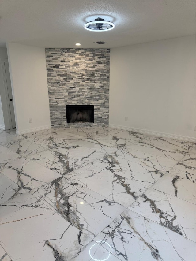 unfurnished living room featuring visible vents, a fireplace, baseboards, and a textured ceiling