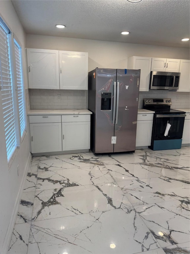 kitchen featuring stainless steel appliances, light countertops, white cabinets, and decorative backsplash