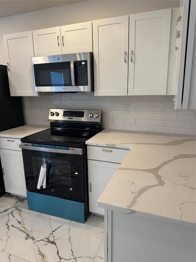 kitchen with marble finish floor, tasteful backsplash, white cabinetry, and stainless steel appliances